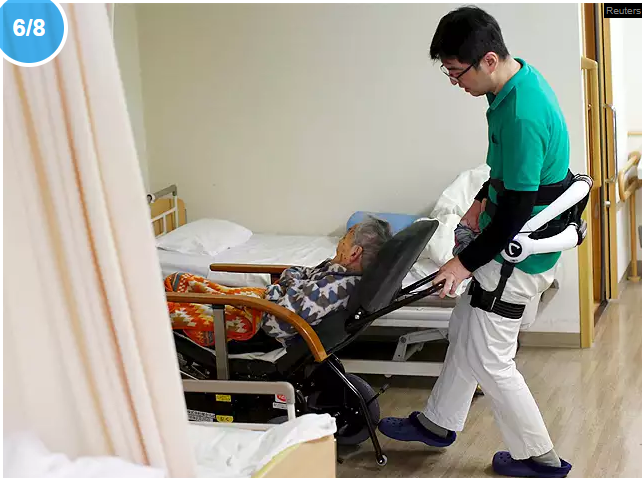 Un soignant habillé avec un ergosquelette pousse un fauteuil roulant à la maison de retraite Shin-tomi à Tokyo