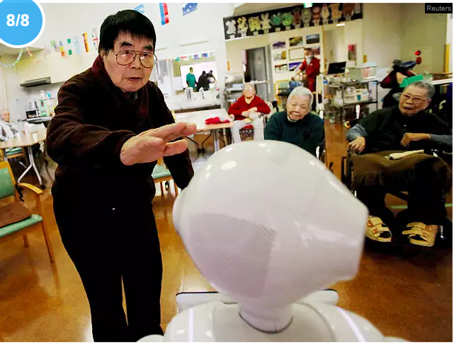 Un résident s'approche du robot humanoïde 'Pepper' pour se caresser la tête lors d'un exercice d'après-midi à la maison de retraite Shin-tomi à Tokyo.